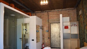 A hotel room with a brick wall, a glass shower enclosure, a bed with white linens, and a wooden headboard. - Arena and Kreshatik, best location, VIP Studio  (Київ)