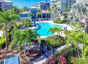 Relax by the resort's central pool surrounded by lush greenery and palm trees.