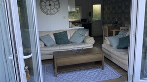 Uma sala de estar com um sofá bege, uma mesa de centro de madeira e um tapete estampado.