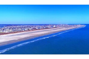 Un paysage urbain côtier avec une vaste plage et une zone urbaine dense en arrière-plan.