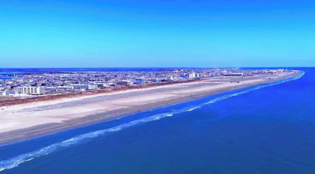 Un paysage urbain côtier avec une vaste plage et une zone urbaine dense en arrière-plan.