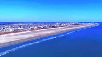 Un paysage urbain côtier avec une vaste plage et une zone urbaine dense en arrière-plan.