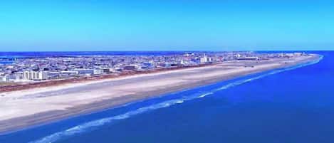 Un paysage urbain côtier avec une vaste plage et une zone urbaine dense en arrière-plan.