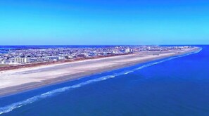 Paesaggio costiero con un'ampia spiaggia e una zona urbana densa sullo sfondo.