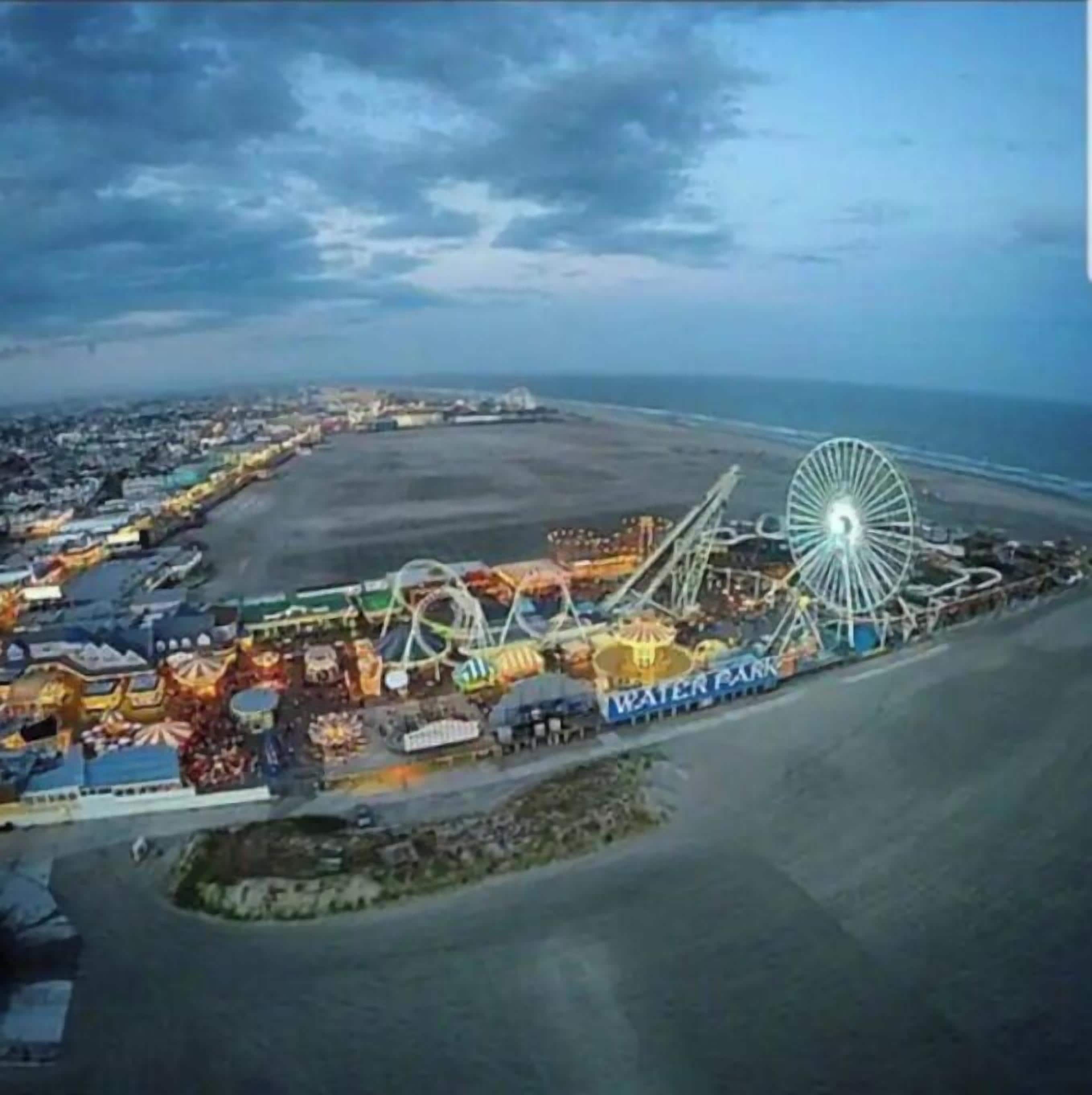 A coastal amusement park with a Ferris wheel and various rides.