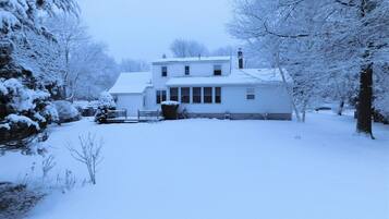 A two-story house with a snow-covered lawn and trees.