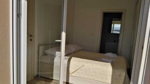 Een slaapkamer met een bed, een nachtkastje en een deur naar de badkamer.