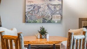 Een eetgedeelte met een houten tafel, landelijke stoelen en een aan de muur hangende kaart.