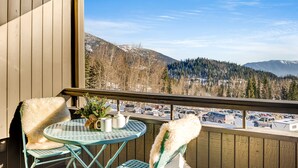 Een balkon met uitzicht op een parkeerplaats en bergen.