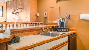 Een keuken met houten aanrecht, een gootsteen, een koffiezetapparaat en een vaatwasser.
