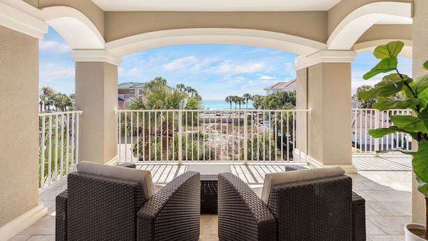 A covered outdoor seating area with wicker furniture and a view of the beach and ocean. - Destiny West, Huge Pool/Spa, Game Room, Gulf Views, Theater, Golf Cart Rental (Destin)