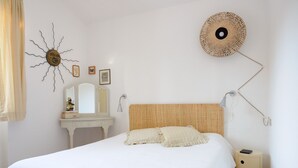 Une chambre avec un grand lit, une commode, un miroir et des œuvres d’art murales.