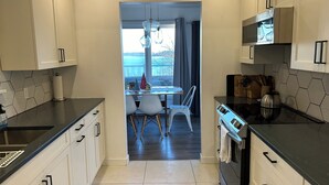 A modern kitchen with white cabinets, a black countertop, and a stainless steel oven.