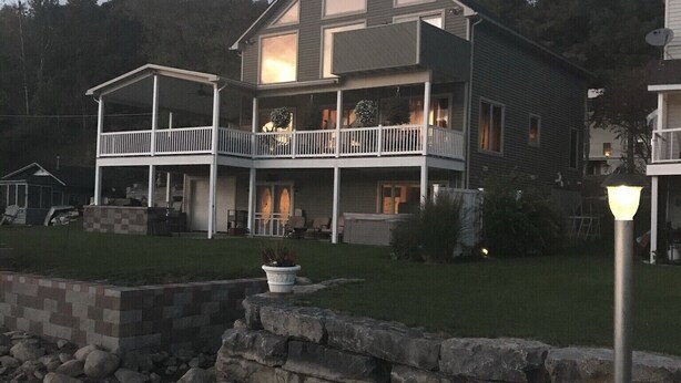 Una casa de dues plantes amb un balcó, un mur de pedra de contenció i un fanal.