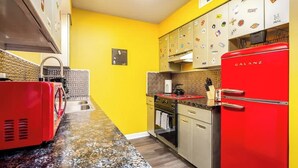 A kitchen with a red refrigerator, a stove, and a sink.