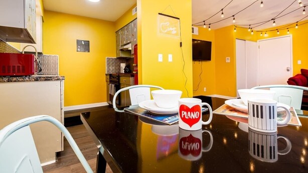 A dining area with a black table, white chairs, and a yellow wall.