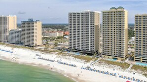 A beachfront hotel with multiple high-rise buildings, a sandy beach, and a pool area.