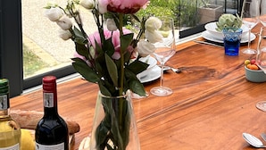 Un tavolo da pranzo con un vaso di fiori, bicchieri da vino e una bottiglia di vino.