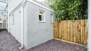 A house with a grey exterior, a wooden fence, and a gravel driveway. - Swansea's Hub (Swansea)