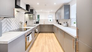 A modern kitchen with herringbone patterned backsplash, stainless steel appliances, and wooden flooring. - Swansea's Hub (Swansea)