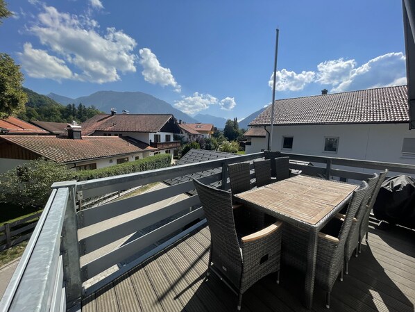 Une terrasse dotée de meubles en osier et offrant une vue sur une chaîne de montagnes.