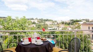 A balcony with a table set for breakfast, overlooking a scenic town. - hotel villa fernanda  (Massa Lubrense)