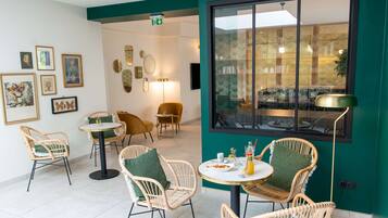 A dining area with wicker chairs, a round table, and a large window with a view of the outside.