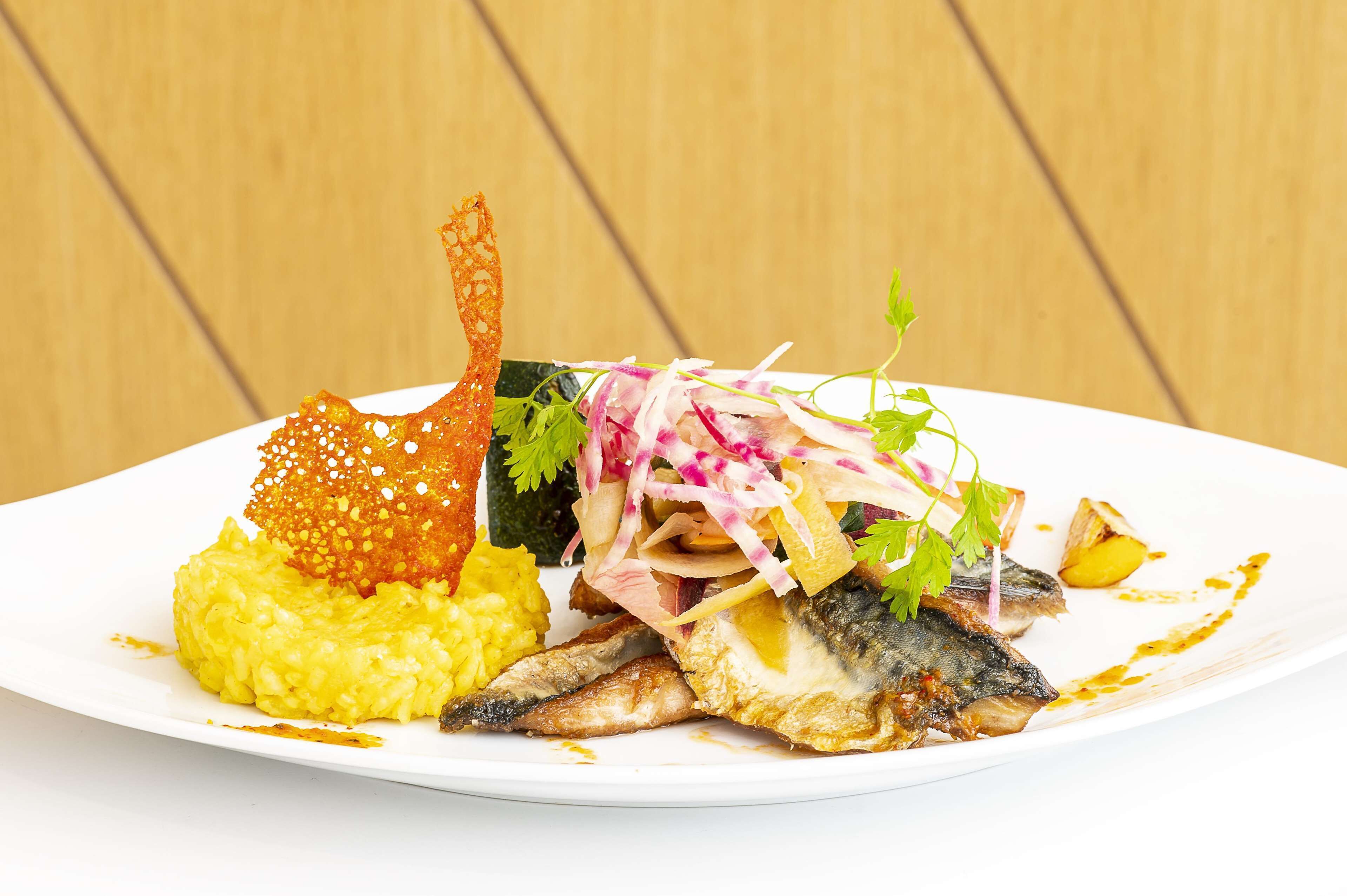 A white plate with a fish, yellow rice, and a decorative element.
