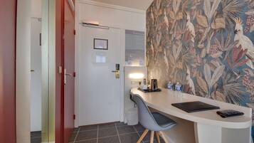 Een kleine kitchenette met een wit aanrecht, een grijze stoel en een laptop.