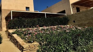 A modern building with a flat roof, a stone retaining wall, and a garden with pink flowers. - Graffeo Countryside Sea View Homes in Menfi in Sicily - Casa delle Rose -  (Menfi)