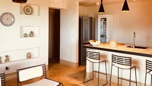 A kitchen with a central island, bar stools, hanging pendant lights, and a refrigerator. - Graffeo Countryside Sea View Homes in Menfi in Sicily - Casa delle Rose -  (Menfi)