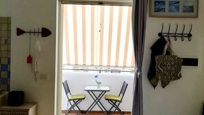 Ein Zimmer mit Balkon, Essbereich und einem an der Wand befestigten Garderobehaken.