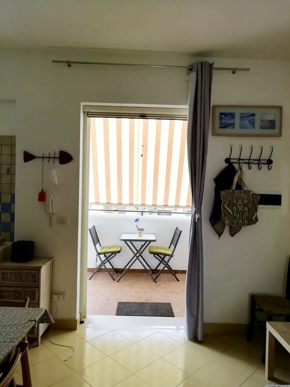 Ein Zimmer mit Balkon, Essbereich und einem an der Wand befestigten Garderobehaken.