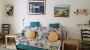 Ein Zimmer mit einem Bett, einem Schreibtisch, Stühlen und Kunstwerken an den Wänden.