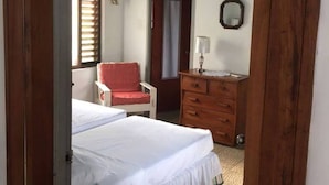 A bedroom with a bed, a chair, a dresser, and a mirror.