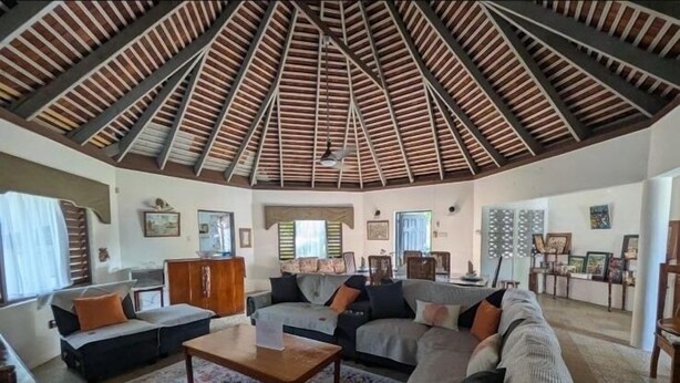 A spacious living area with a high, sloped ceiling and a central coffee table.