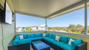 A covered outdoor seating area with a large sectional sofa and two coffee tables.