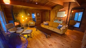 Een gezellig chalet interieur met een houten vloer, een zithoek, een eettafel en een blauwe stoel.