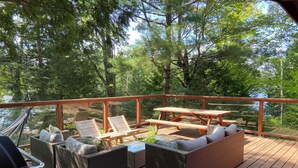Een houten terras met rieten meubels, een picknicktafel en een barbecue.