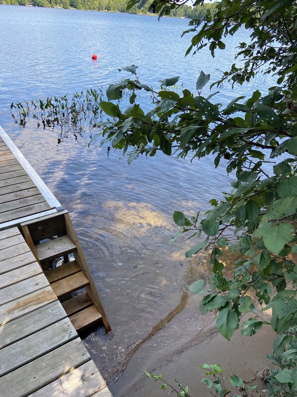 Une jetée en bois s’étendant sur un lac paisible aux eaux limpides.