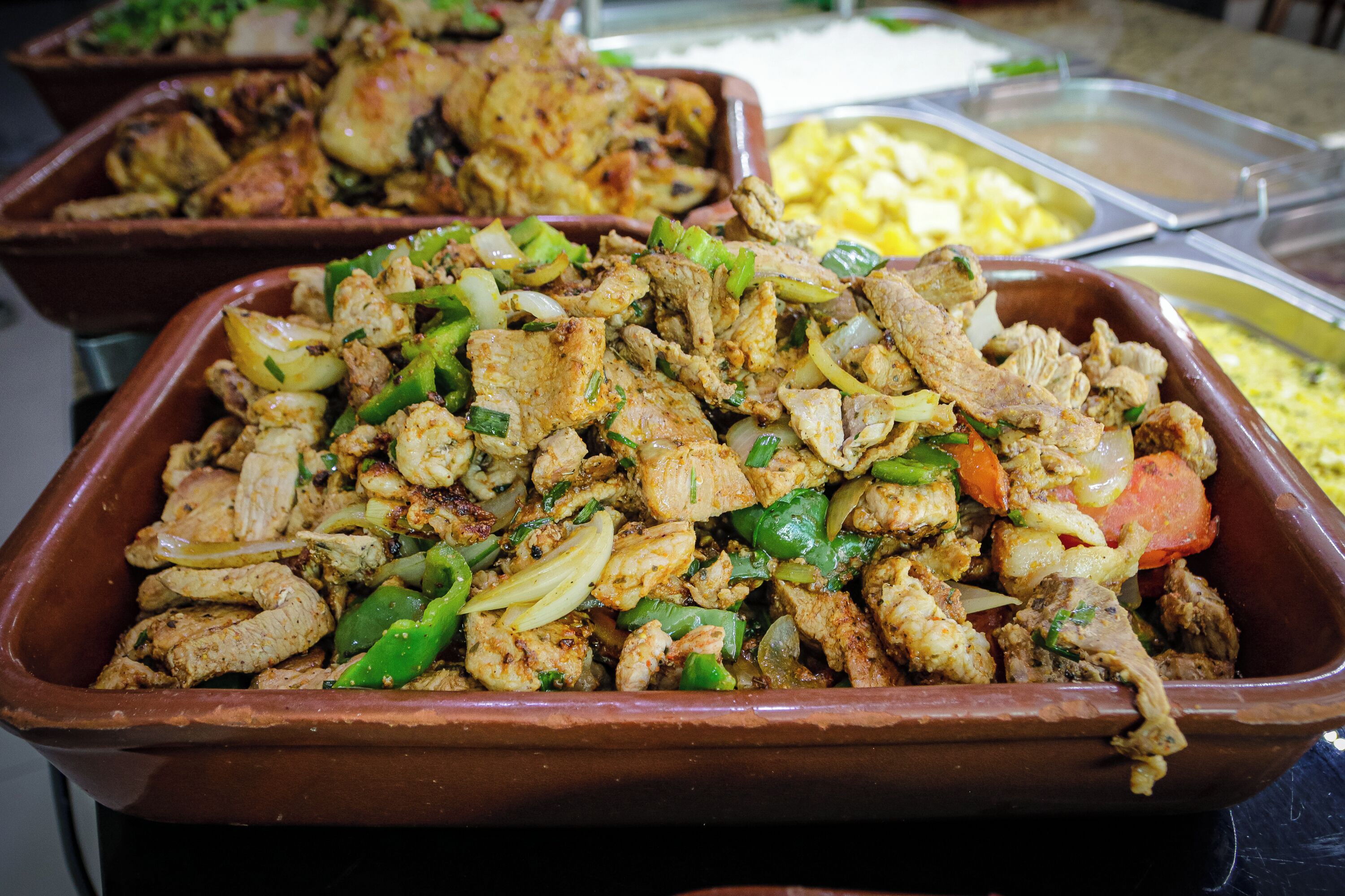 Un bufé con diversos platos, incluyendo carne y verduras salteadas.