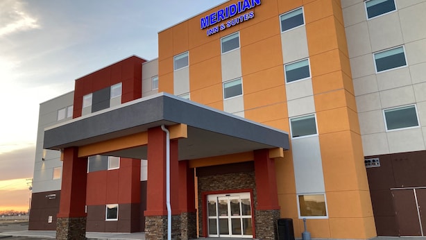 Um hotel moderno com uma placa de destaque que diz "MERIDIAN INN & SUITES".