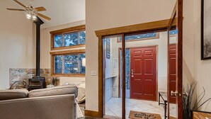 A cozy living room with a sofa, a fireplace, and a ceiling fan. - Mountain View Retreat - Epic Views, Pool Table & Garage (Rollinsville)