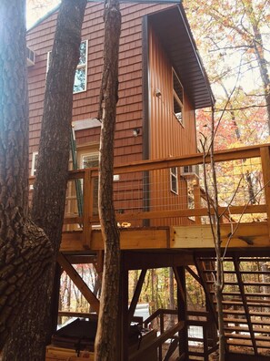 A multi-level wooden cabin with a balcony, surrounded by trees. - Barn Owl Inn Treehouse - Private Hot Tub (Guild)