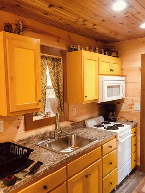 A compact kitchen with wooden cabinets, a white stove, and a sink.