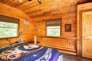 A wooden cabin bedroom with a bed, windows, and a door. - Barn Owl Inn Treehouse - Private Hot Tub (Guild)