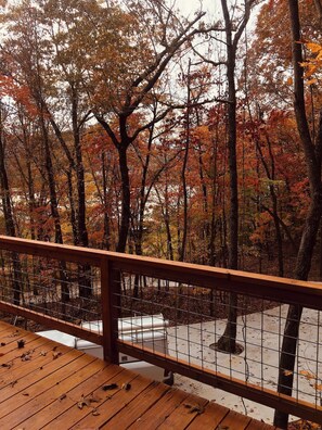 A wooden deck with a metal railing overlooking a forested area with autumn foliage. - Barn Owl Inn Treehouse - Private Hot Tub (Guild)