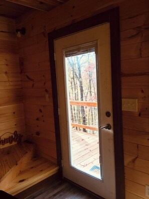 A wooden cabin interior with a door leading to a deck. - Barn Owl Inn Treehouse - Private Hot Tub (Guild)