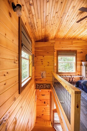 A wooden cabin interior with a staircase leading to a loft bed area. - Barn Owl Inn Treehouse - Private Hot Tub (Guild)