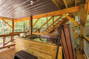 A wooden cabin with a wooden deck, a hot tub, and a bench. - Barn Owl Inn Treehouse - Private Hot Tub (Guild)